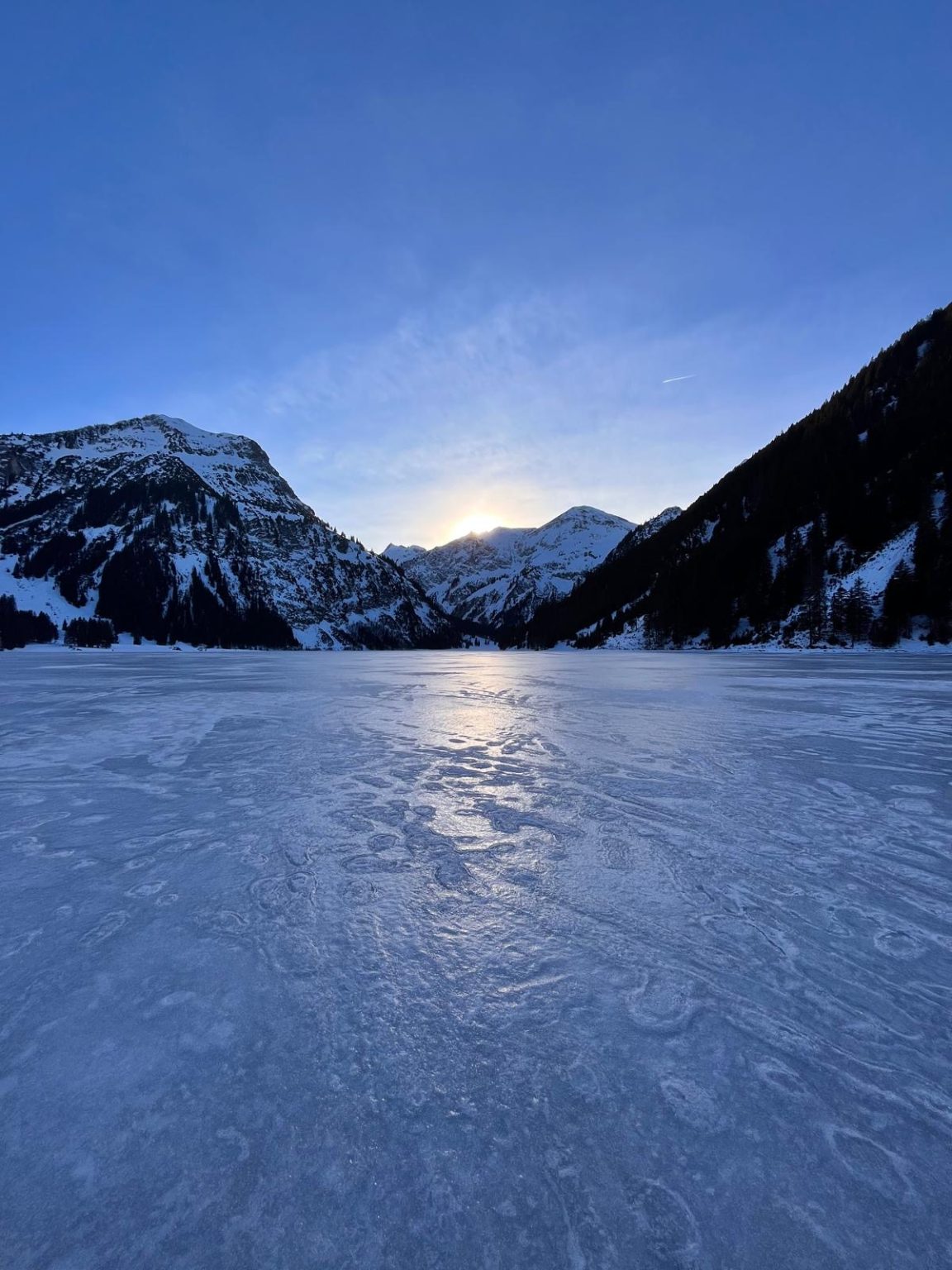 Sonnenaufgang über dem zugefrorenen Bergsee
